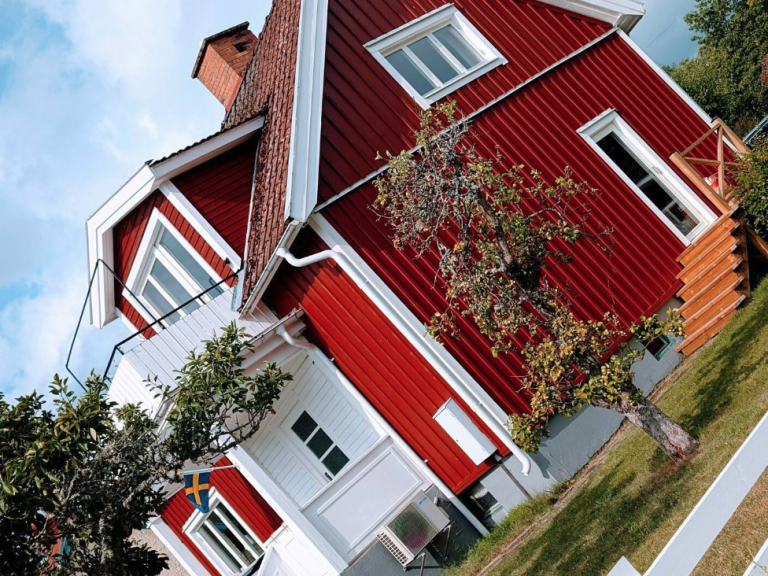 Rotes Holzhaus Schweden mit weißen Fenstern und Garten im Vordergrund.