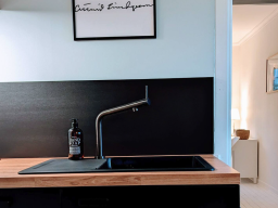Moderne Küche mit schwarzem Spültisch und Wasserhahn auf Holzoberfläche.
